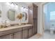 Bathroom with a double sink vanity, granite countertop, and wood cabinets and a view into the shower at 29118 Picana Ln, Wesley Chapel, FL 33543