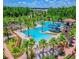 Aerial view of a luxurious community pool featuring water slides, palm trees, and plenty of lounge chairs at 29118 Picana Ln, Wesley Chapel, FL 33543