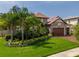 Stunning exterior of a stone home featuring a three-car garage, lush landscaping, and a tile roof at 29118 Picana Ln, Wesley Chapel, FL 33543