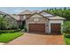 Charming stone-faced home with a brick driveway and a three-car garage offers curb appeal and convenience at 29118 Picana Ln, Wesley Chapel, FL 33543
