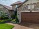 Charming home featuring a stone facade, manicured landscaping, and a three-car garage at 29118 Picana Ln, Wesley Chapel, FL 33543