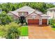 Attractive exterior of a stone home boasting a brick driveway, three-car garage, and tile roof at 29118 Picana Ln, Wesley Chapel, FL 33543