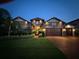 Nighttime view of the home's exterior highlighting the stone facade, manicured lawn, and three-car garage at 29118 Picana Ln, Wesley Chapel, FL 33543