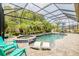 Inviting pool with a spa, screened enclosure, lush landscaping, and lounge chairs at 29118 Picana Ln, Wesley Chapel, FL 33543