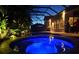 Nighttime view of a sparkling pool and spa under a screened enclosure, illuminated with vibrant blue lighting at 29118 Picana Ln, Wesley Chapel, FL 33543