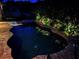 Night view of the pool and spa area, featuring lush landscaping and cozy lounge chairs for relaxation at 29118 Picana Ln, Wesley Chapel, FL 33543