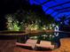 Relaxing poolside view with lounge chairs, spa, and grill, surrounded by lush landscaping and a screened enclosure at 29118 Picana Ln, Wesley Chapel, FL 33543
