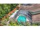 Aerial view of a backyard featuring a screened-in pool, landscaped yard, and a wooden privacy fence at 2973 Spring Oak Ct, Palm Harbor, FL 34684