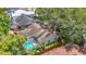 Aerial view highlighting a home with a screened-in pool, lush landscaping, and a wooden privacy fence at 2973 Spring Oak Ct, Palm Harbor, FL 34684