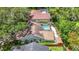 Aerial perspective of a home boasting a screened pool, landscaped yard, wooden fence and storage shed among mature trees at 2973 Spring Oak Ct, Palm Harbor, FL 34684