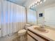 Neutral bathroom featuring a bathtub with curtain, vanity with beige sink, and bright vanity lights at 2973 Spring Oak Ct, Palm Harbor, FL 34684