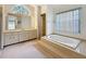 Large Primary bathroom with soaking tub, bright vanity lighting, and lots of counter space at 2973 Spring Oak Ct, Palm Harbor, FL 34684