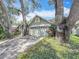 Exterior of home showcasing mature trees, well-maintained lawn, and two-car garage at 2973 Spring Oak Ct, Palm Harbor, FL 34684