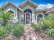 Inviting home front with a brick walkway leading to the arched doorway entrance and lush, manicured landscaping at 2973 Spring Oak Ct, Palm Harbor, FL 34684