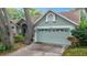 Exterior view of a well-maintained home featuring a two-car garage and lush landscaping at 2973 Spring Oak Ct, Palm Harbor, FL 34684