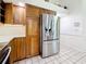 Well-equipped kitchen with stainless steel refrigerator, wood cabinets, tile backsplash, and solid surface countertops at 2973 Spring Oak Ct, Palm Harbor, FL 34684