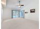 Open living room featuring ceiling fan, sliding glass doors leading to the pool, and neutral carpet at 2973 Spring Oak Ct, Palm Harbor, FL 34684