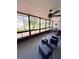 Enclosed lanai with exercise equipment, ceiling fan, seating, and view of green backyard at 30 Tads Trl, Oldsmar, FL 34677