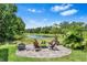 Backyard fire pit and comfortable seating with a tranquil lake view and lush greenery at 30801 Parrot Reef Ct, Wesley Chapel, FL 33545