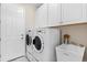 Well-organized laundry room with white cabinets, sink, and modern washer and dryer units by the back door at 30801 Parrot Reef Ct, Wesley Chapel, FL 33545