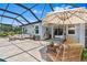 Stylish screened-in patio with an umbrella, comfortable seating, and lush backyard view at 30801 Parrot Reef Ct, Wesley Chapel, FL 33545