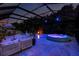 Enclosed pool area with a relaxing spa, outdoor lounge, and vibrant pool lighting at 30801 Parrot Reef Ct, Wesley Chapel, FL 33545