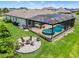Aerial view of a screened-in pool and spa area with a fire pit and plenty of seating at 30801 Parrot Reef Ct, Wesley Chapel, FL 33545