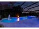 Inviting screened pool and spa illuminated with colorful lights for nighttime enjoyment at 30801 Parrot Reef Ct, Wesley Chapel, FL 33545