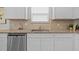 Close-up of a kitchen sink with granite countertop, stainless steel dishwasher and travertine backsplash at 3935 Capri Coast Dr, Plant City, FL 33565