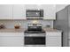 Modern kitchen features stainless steel appliances, granite countertops, white cabinets, and tile backsplash at 3935 Capri Coast Dr, Plant City, FL 33565