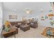 Cozy living room featuring a brown leather sectional sofa, tile floors, and ample natural light at 3935 Capri Coast Dr, Plant City, FL 33565