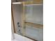 Close-up of a shower/tub area with gold trim and clear glass doors providing bright and modern aesthetic at 400 Island Way # 1402, Clearwater Beach, FL 33767