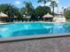 Large pool area, featuring clear blue water, tiki huts, lounge chairs, and well-maintained landscaping at 400 Island Way # 1402, Clearwater Beach, FL 33767
