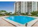 Large, bright blue swimming pool with tiled deck, landscaping, and a high-rise condo building in the background at 400 Island Way # 1402, Clearwater Beach, FL 33767