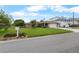 Charming single-story home featuring a manicured lawn, mature trees, and a large driveway leading to a garage at 4299 Bellaire Dr, Hernando Beach, FL 34607