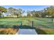 Tennis court with green fencing, lush trees, and a clear blue sky in a beautiful park setting at 4612 35Th E Ave, Palmetto, FL 34221