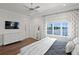 Bright bedroom with a queen bed, hardwood floors, a dresser, and decorative curtains at 5110 W Longfellow Ave, Tampa, FL 33629