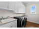 Well-lit laundry room featuring updated washer and dryer, custom cabinetry, and sink at 5110 W Longfellow Ave, Tampa, FL 33629