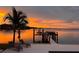 A picturesque waterfront view featuring a private dock, boat lift, and lounge chairs, set against a vibrant sunset at 5110 W Longfellow Ave, Tampa, FL 33629
