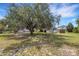 Expansive backyard with mature trees and storage sheds, providing ample space for outdoor activities at 5250 Brody Blvd, Wimauma, FL 33598