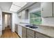 Kitchen featuring a stainless steel sink, granite countertops, white cabinets, and a bright skylight at 5250 Brody Blvd, Wimauma, FL 33598