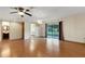 Open living room with hardwood floors, ceiling fan, sliding glass doors, and an open doorway at 5250 Brody Blvd, Wimauma, FL 33598