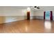 A simple living room with hardwood floors, ceiling fan, wall details, and a wooden door at 5250 Brody Blvd, Wimauma, FL 33598