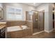This bathroom features a soaking tub and shower encased in beautiful earth-toned tiling and a bright window at 610 Winterside Dr, Apollo Beach, FL 33572