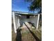 View of the backyard area with covered carport, featuring a concrete slab, and a peek at the sunny skies at 708 Rutgers Pl, Sun City Center, FL 33573