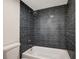 Stylish bathroom featuring a white bathtub and shower with unique dark tile at 739 1St Ct, Palm Harbor, FL 34684