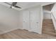 Bright bedroom featuring light wood floors, ceiling fan and two closets with a staircase in the background at 739 1St Ct, Palm Harbor, FL 34684