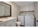 Bright laundry room with modern sink, mirror, white cabinets and a new washer and dryer set at 739 1St Ct, Palm Harbor, FL 34684