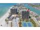 Aerial view of a high-rise condominium building next to the beach, with amenities like tennis courts and a pool at 7600 Bayshore Dr # 1201A, Treasure Island, FL 33706