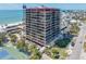 Exterior of a tall condominium building with multiple floors, balconies, ocean view, and tennis courts in front at 7600 Bayshore Dr # 1201A, Treasure Island, FL 33706